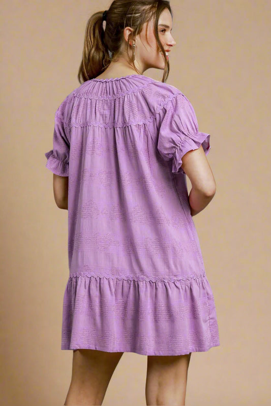 Woman wearing a lavender dress against a beige background