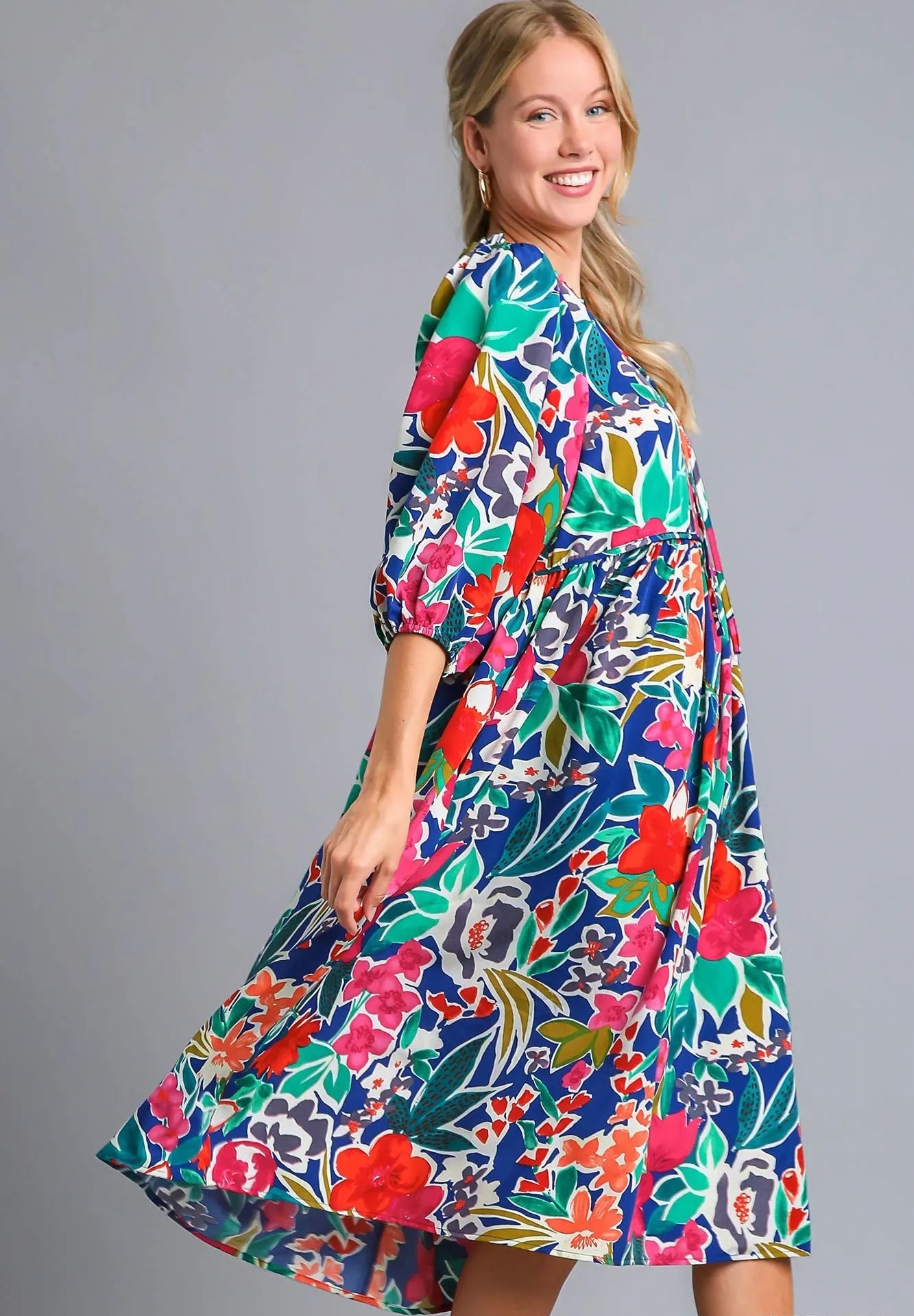 Woman wearing a colorful floral dress on a gray background