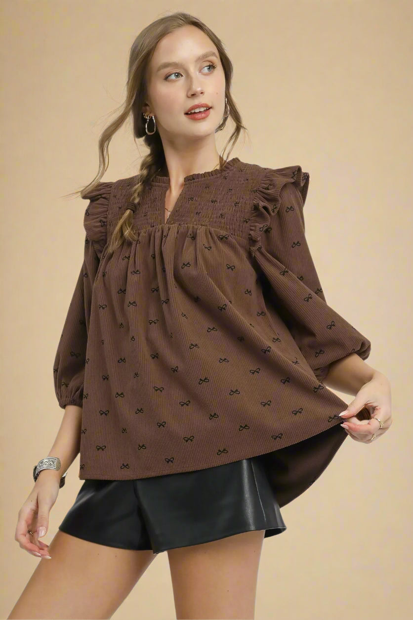 Woman wearing a brown blouse with puff sleeves on a beige background