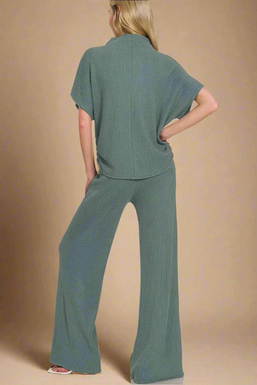 Woman wearing a green outfit with wide-leg pants on a beige background