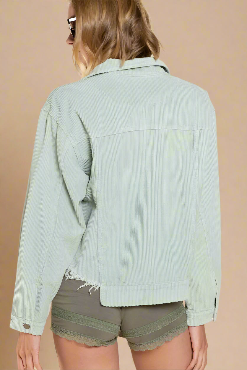 Person wearing a light green corduroy jacket and green shorts on a beige background