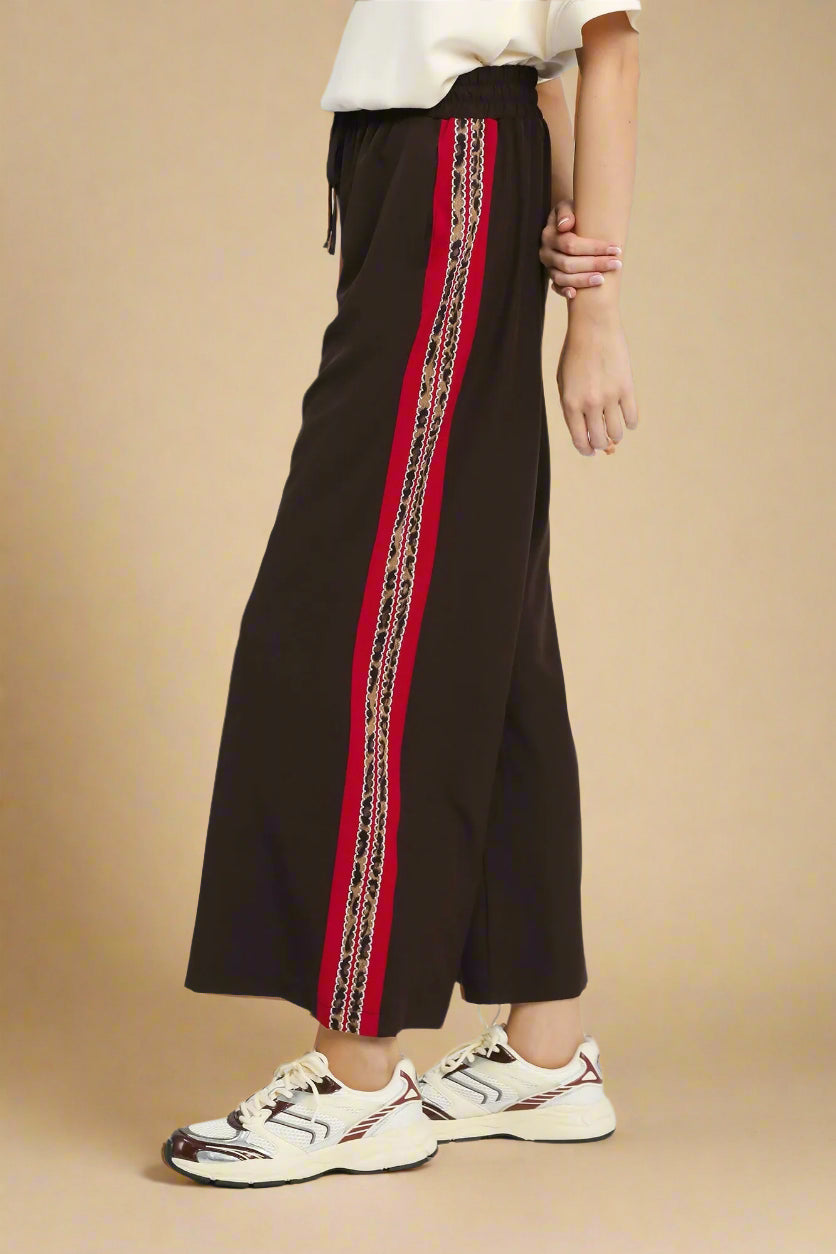 Brown wide-leg pants with a red and gold stripe on a white background