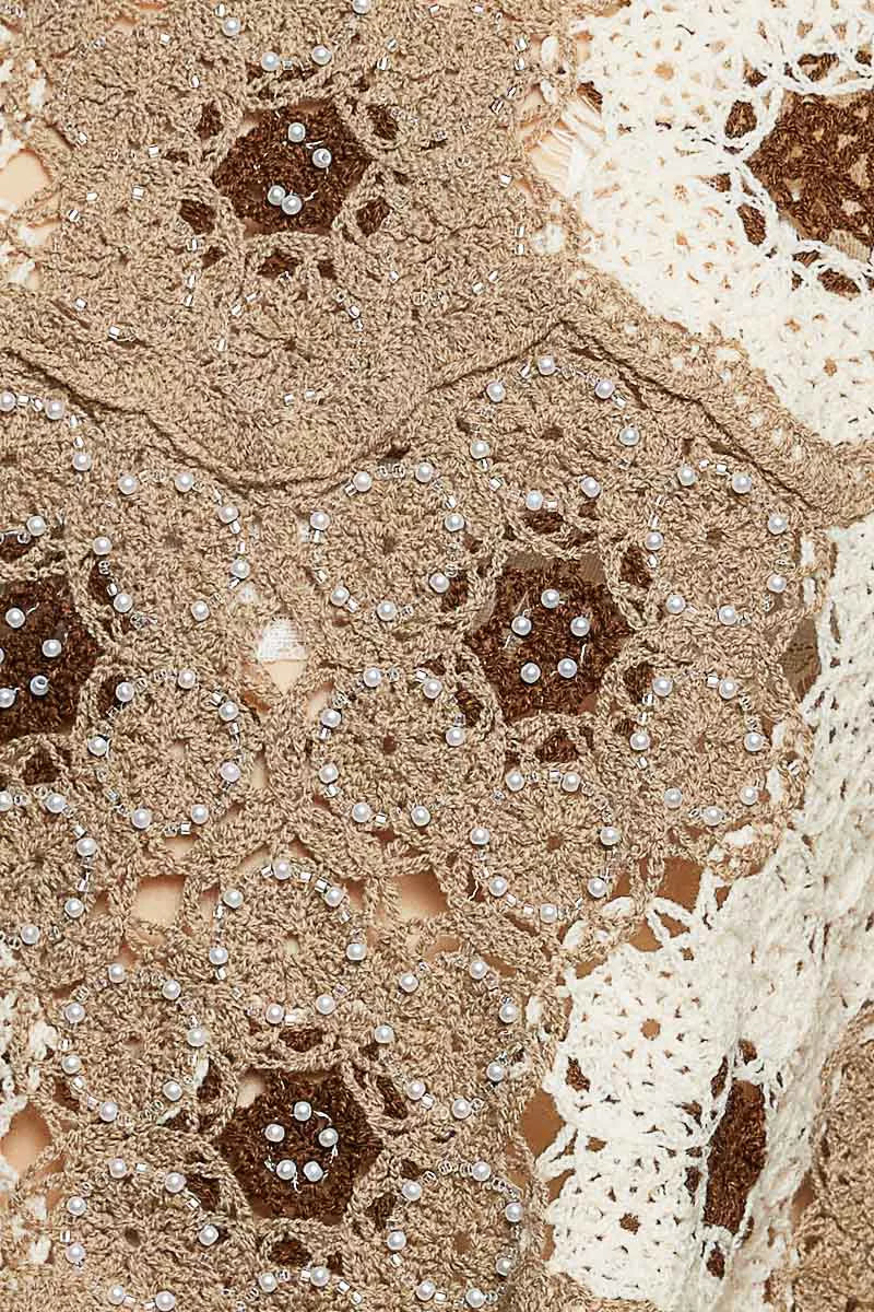 Close-up of a textured fabric with floral patterns and beadwork.