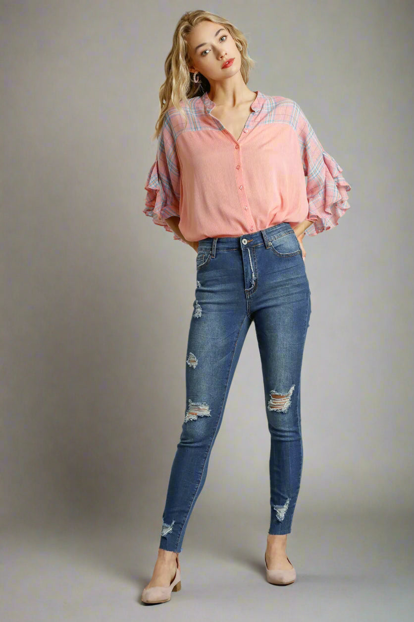 Woman wearing a pink plaid shirt and blue jeans on a gray background