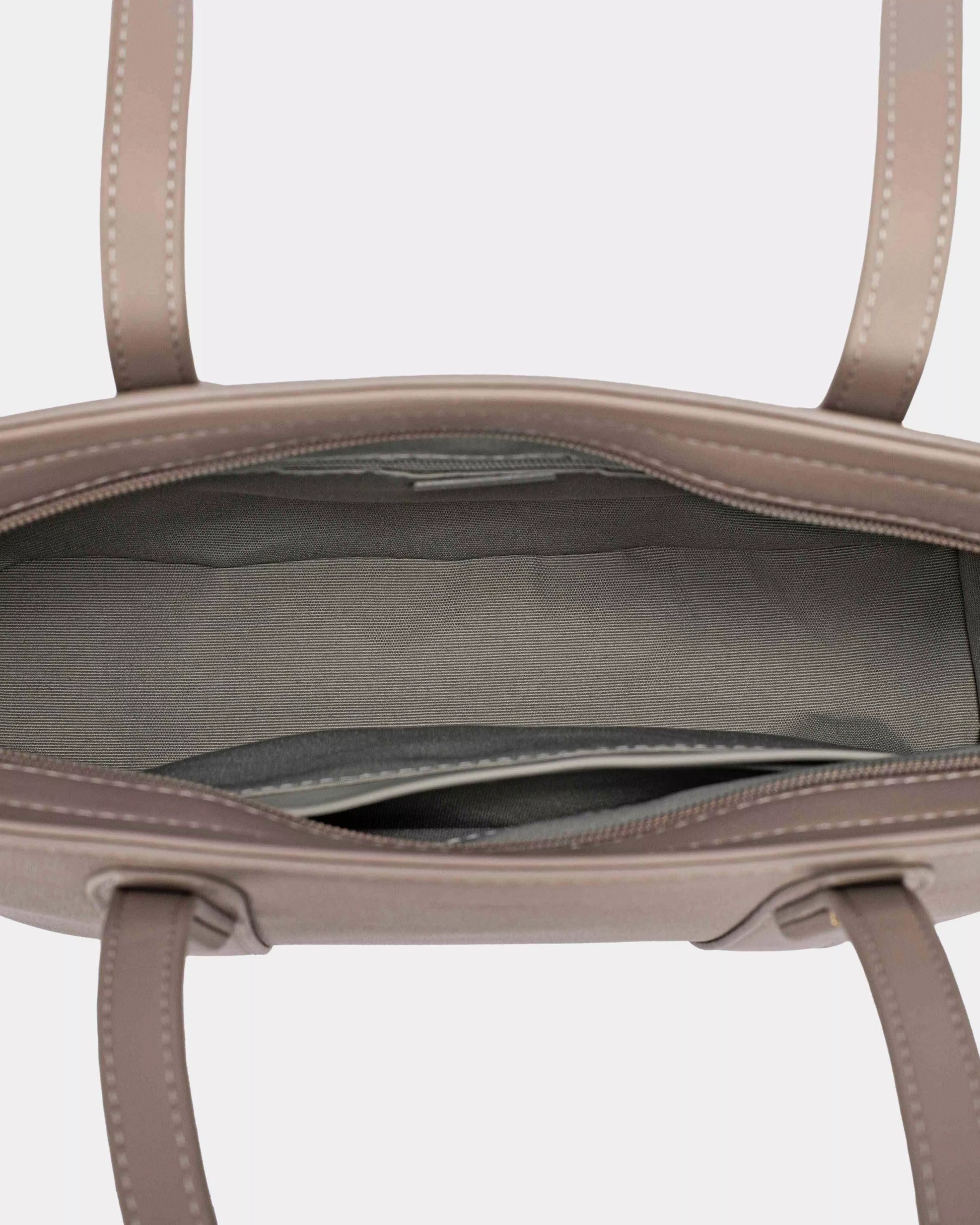 Close-up of a beige handbag with visible stitching on a light gray background