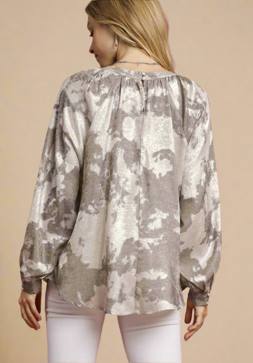 Woman wearing a taupe floral blouse against a beige background