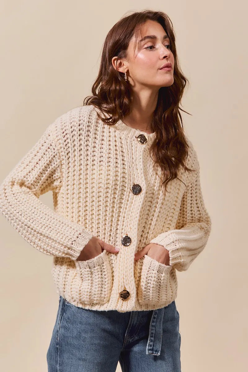Woman wearing a beige knitted cardigan with buttons on a beige background