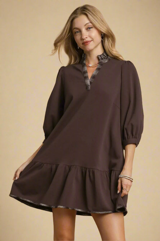 Woman wearing a brown dress with a fur collar against a beige background