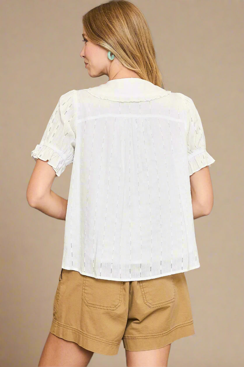 Woman wearing a white blouse and beige shorts against a beige background