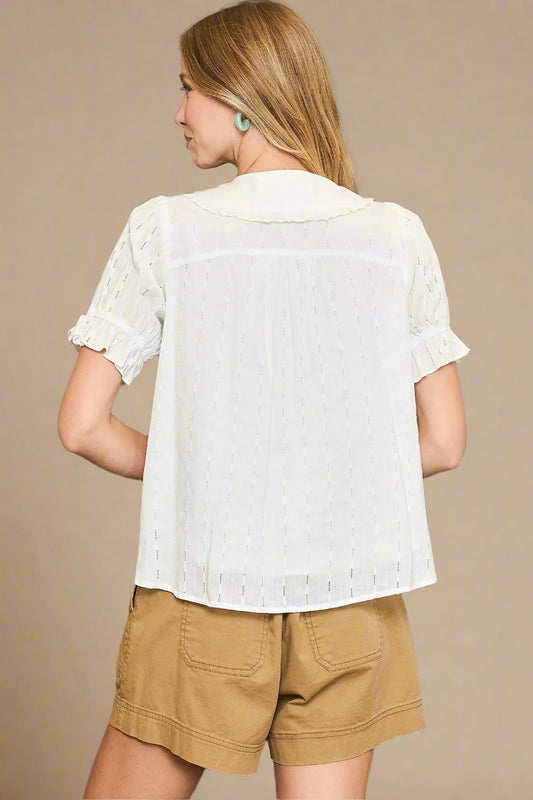 Woman wearing a white blouse and beige shorts against a beige background