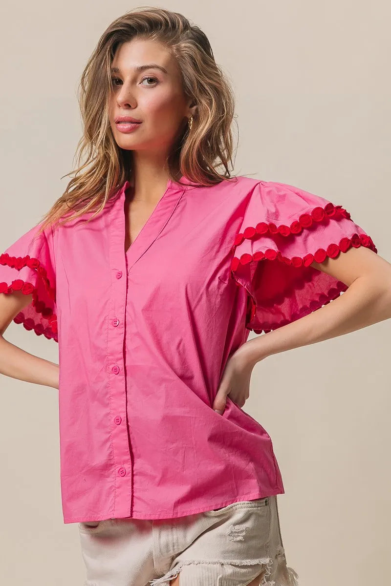 Woman wearing a pink blouse with ruffled sleeves on a beige background
