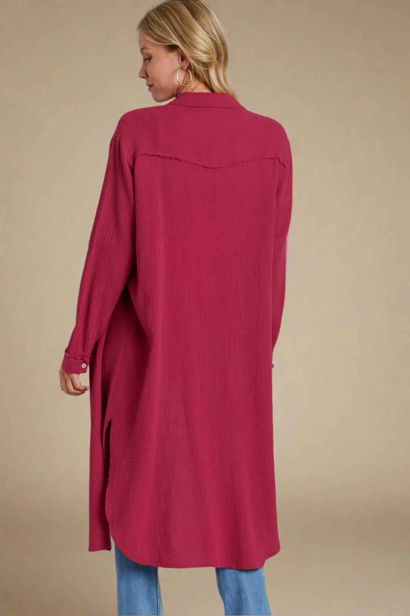Woman wearing a long burgundy shirt with a plain background