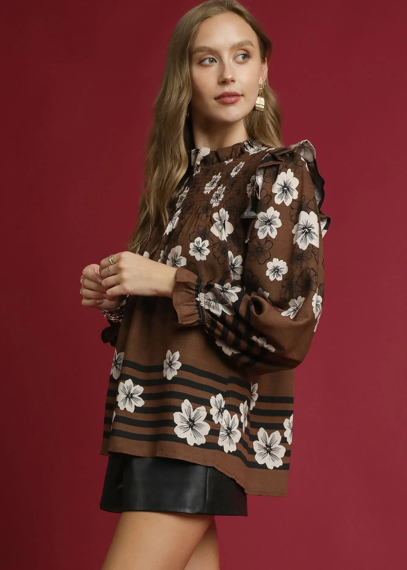 Woman wearing a brown floral blouse with a red background