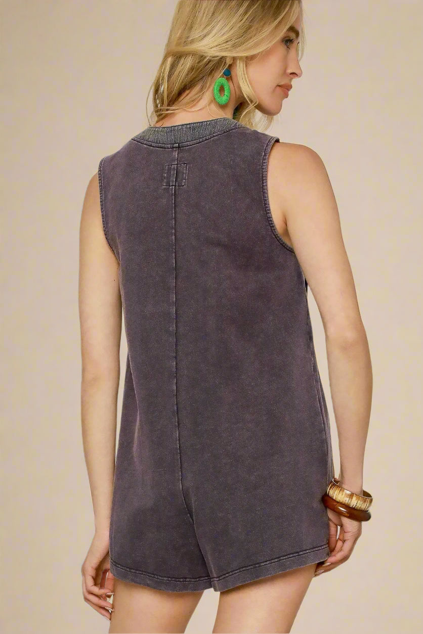 Woman wearing a sleeveless navy romper against a plain background