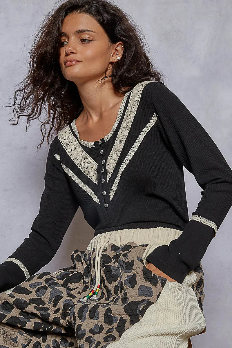 Woman wearing a black sweater with white accents and leopard print pants against a gray background