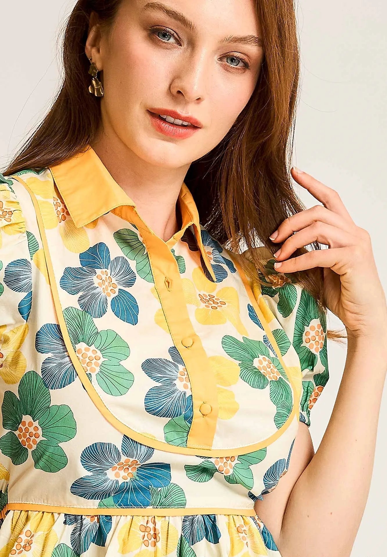 Woman wearing a floral dress with yellow accents against a plain background