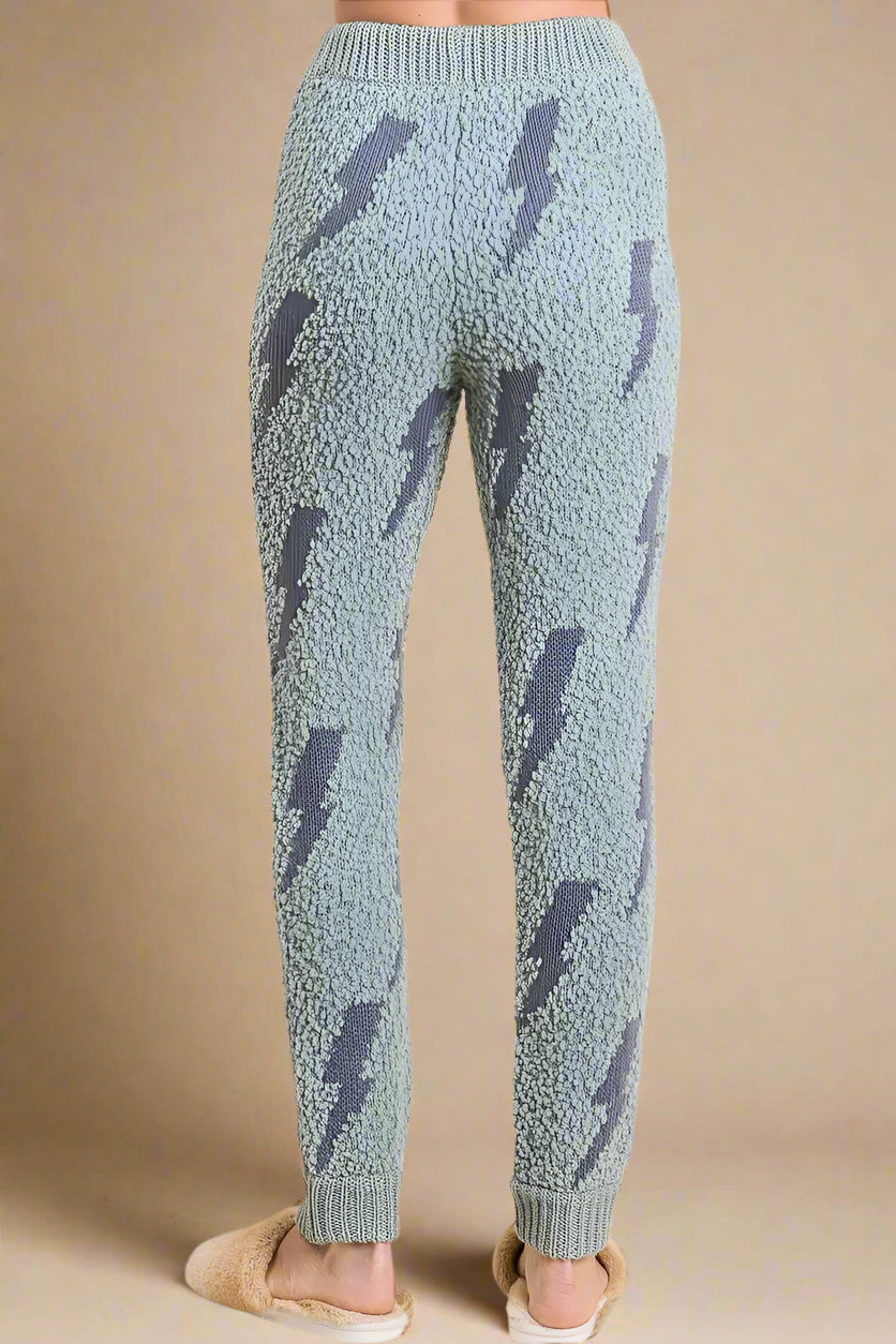Light blue knitted pants with dark blue lightning bolt pattern on a beige background