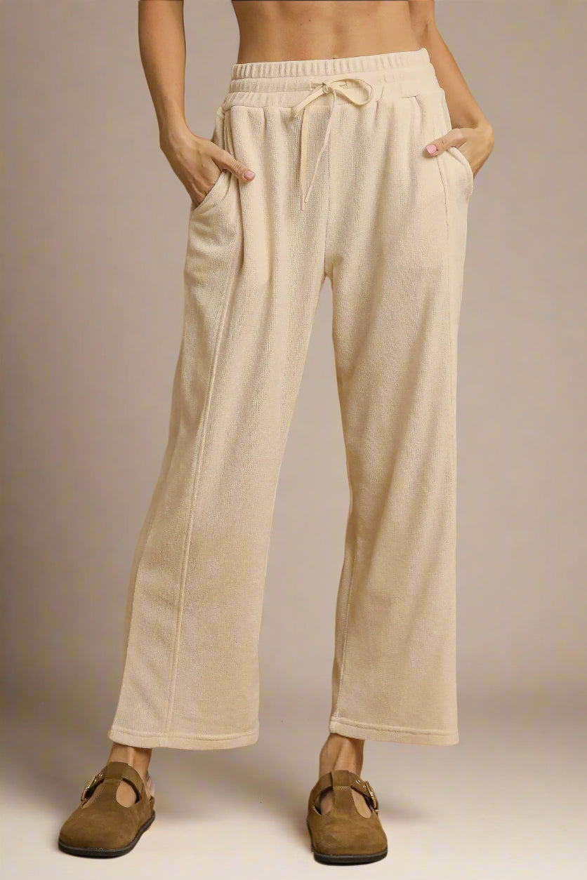 Cream-colored pants worn by a person on a beige background