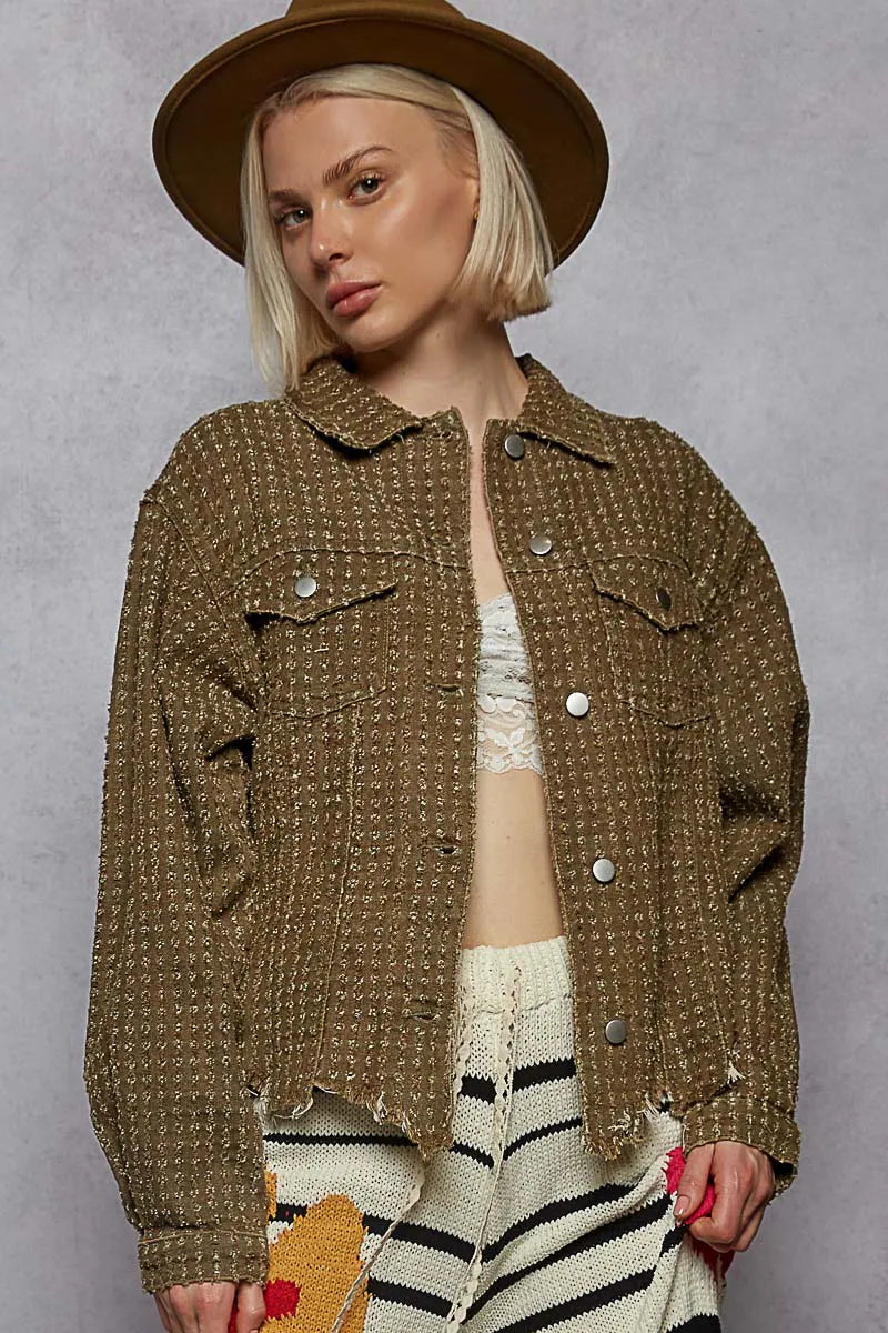 Woman wearing a brown textured jacket and hat against a gray background