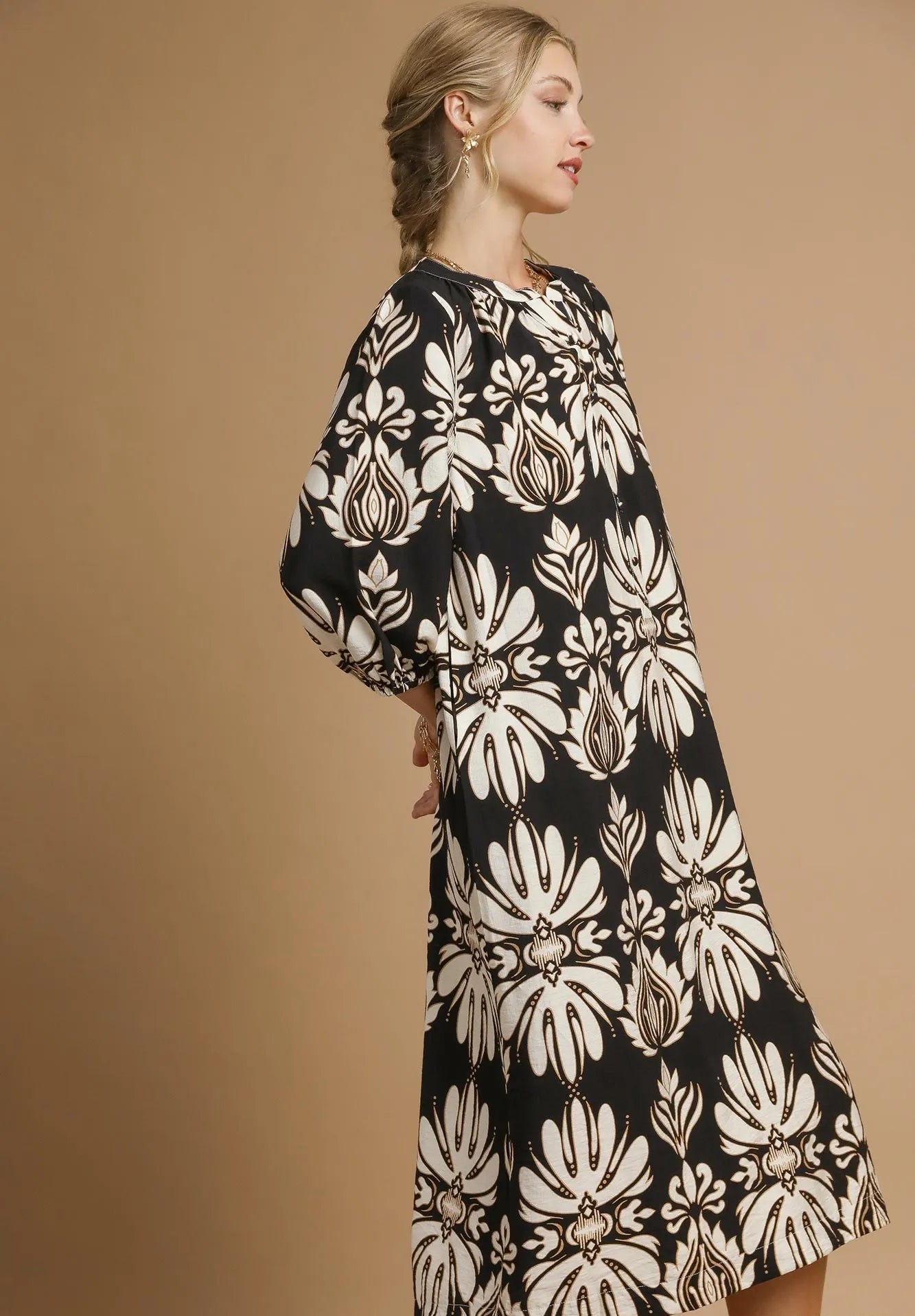 Woman wearing a black and white floral dress against a beige background