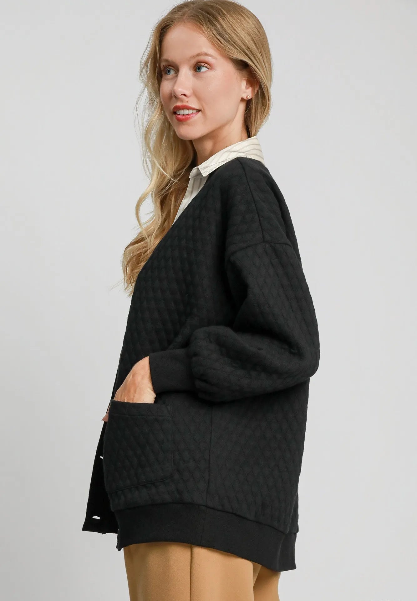 Woman wearing a black sweater with a white collar against a light gray background