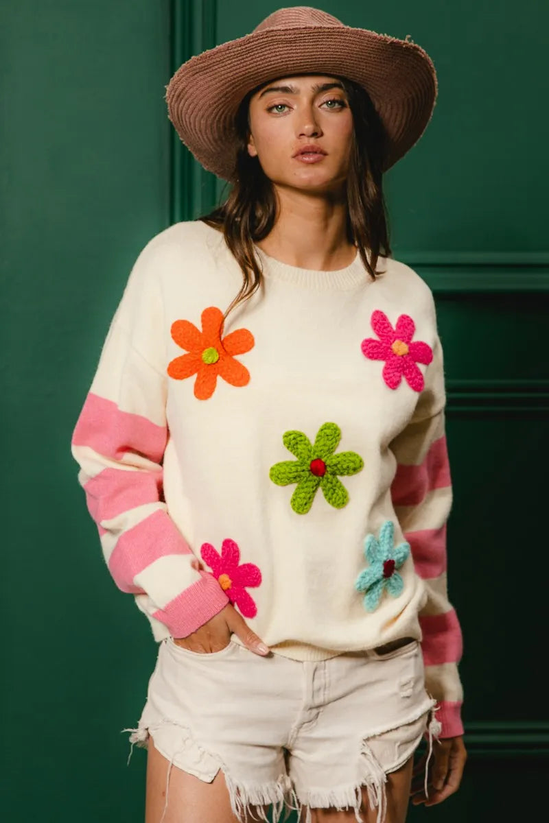 Woman wearing a sweater with colorful flower appliqués against a green background