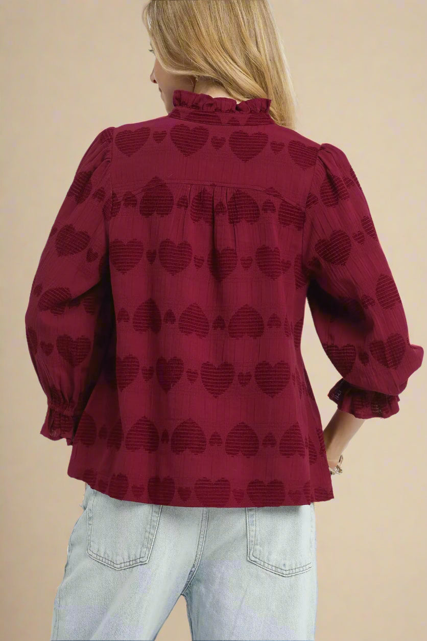 Red blouse with heart pattern worn by a person on a white background