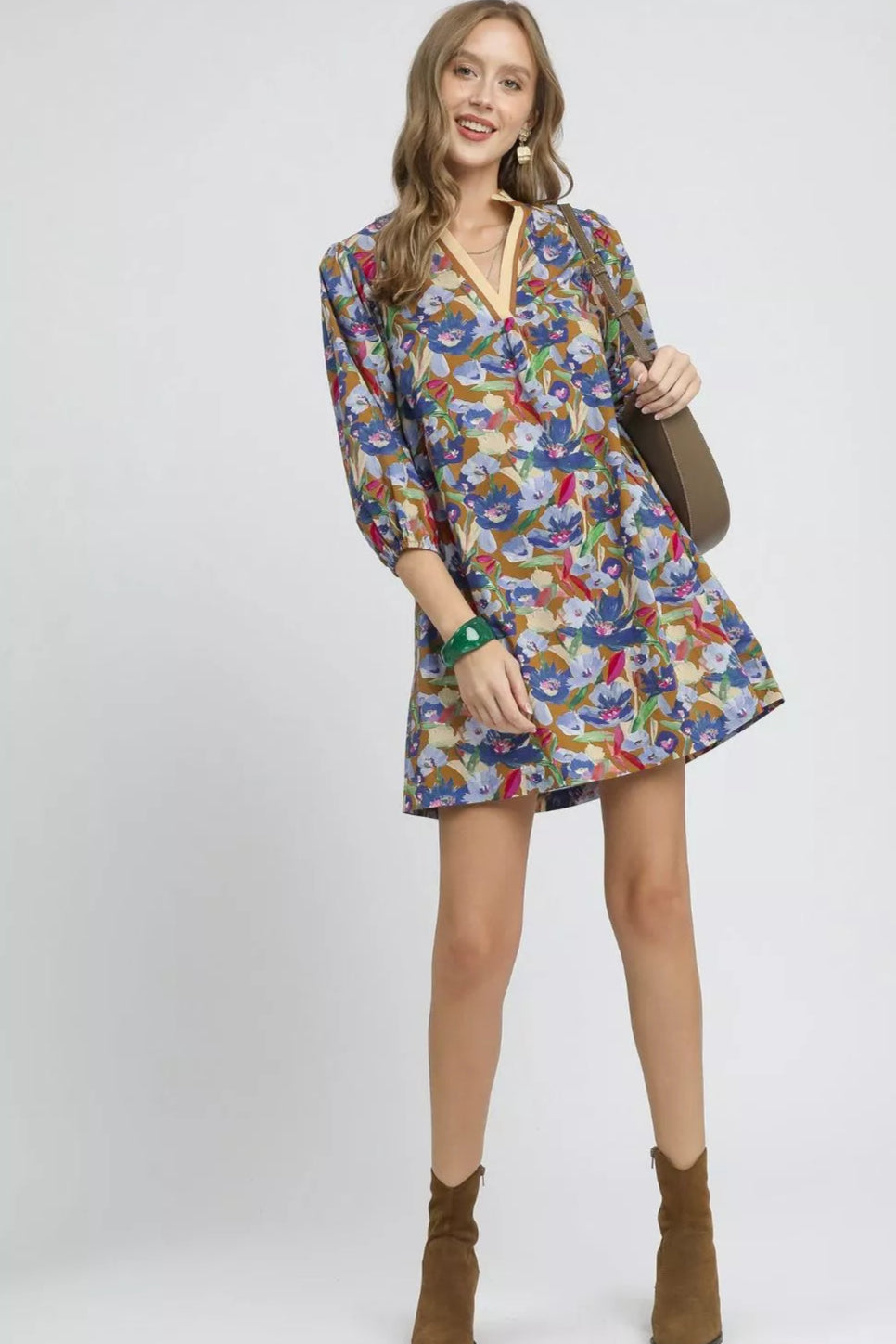Woman wearing a colorful floral dress with brown boots on a white background