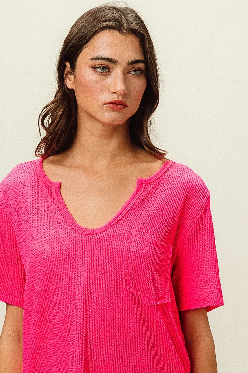 Woman wearing a pink textured top against a plain background