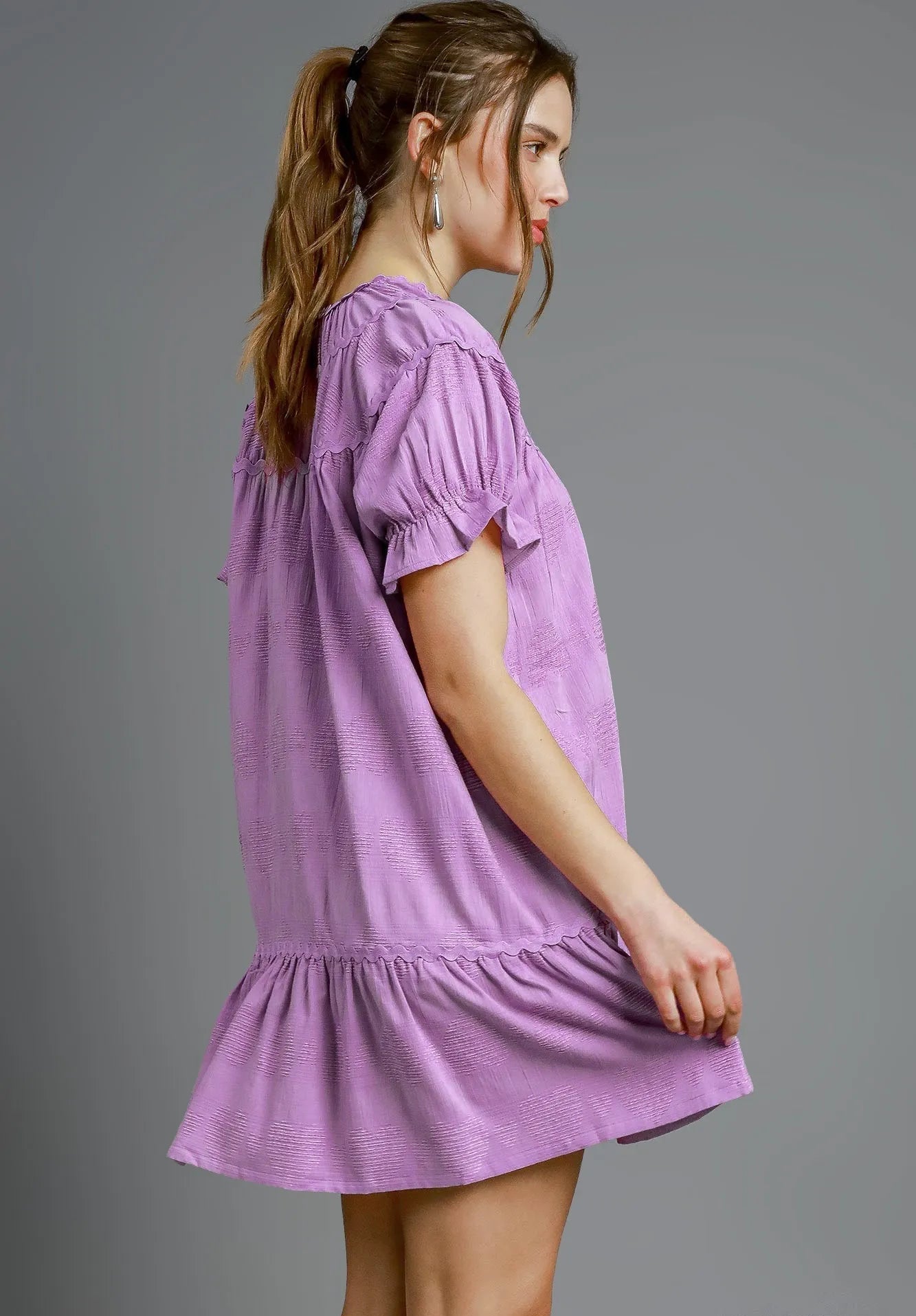 Woman wearing a lavender dress against a gray background