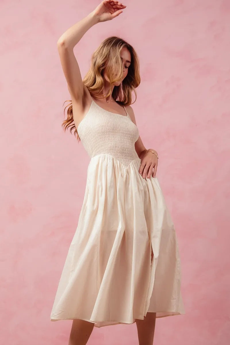 Woman in a white dress posing against a pink background