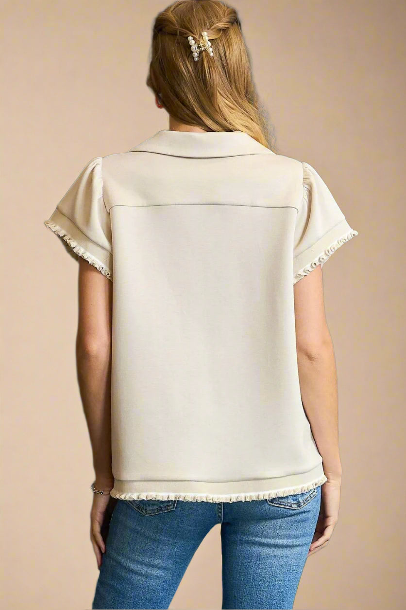 Woman wearing a beige top with short sleeves and blue jeans against a beige background