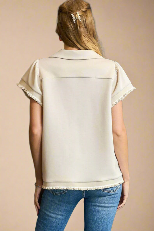 Woman wearing a beige top with short sleeves and blue jeans against a beige background