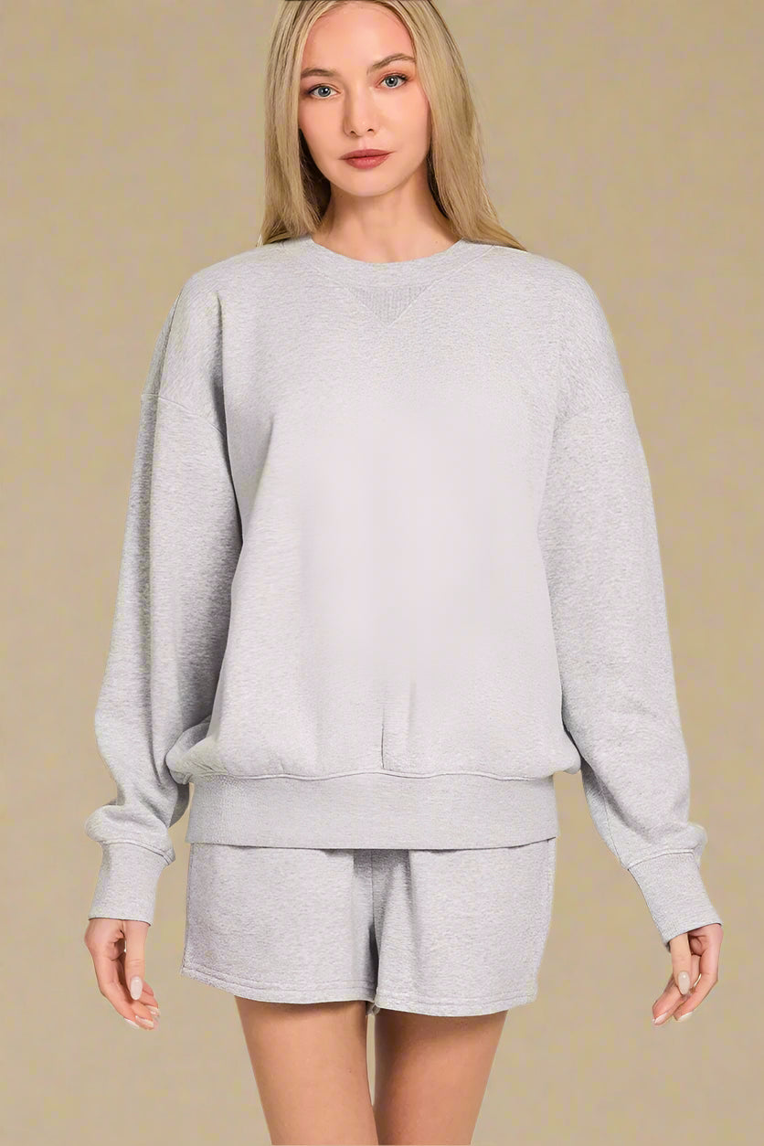 Woman wearing a gray sweatshirt and shorts set on a beige background