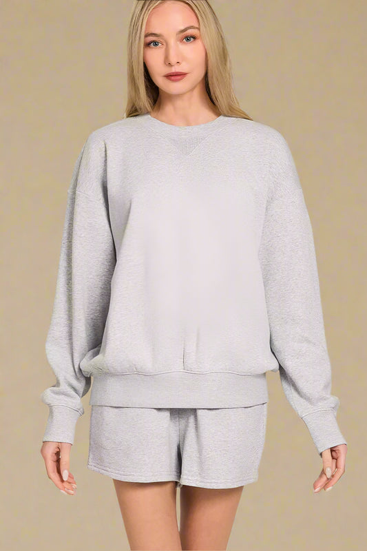 Woman wearing a gray sweatshirt and shorts set on a beige background