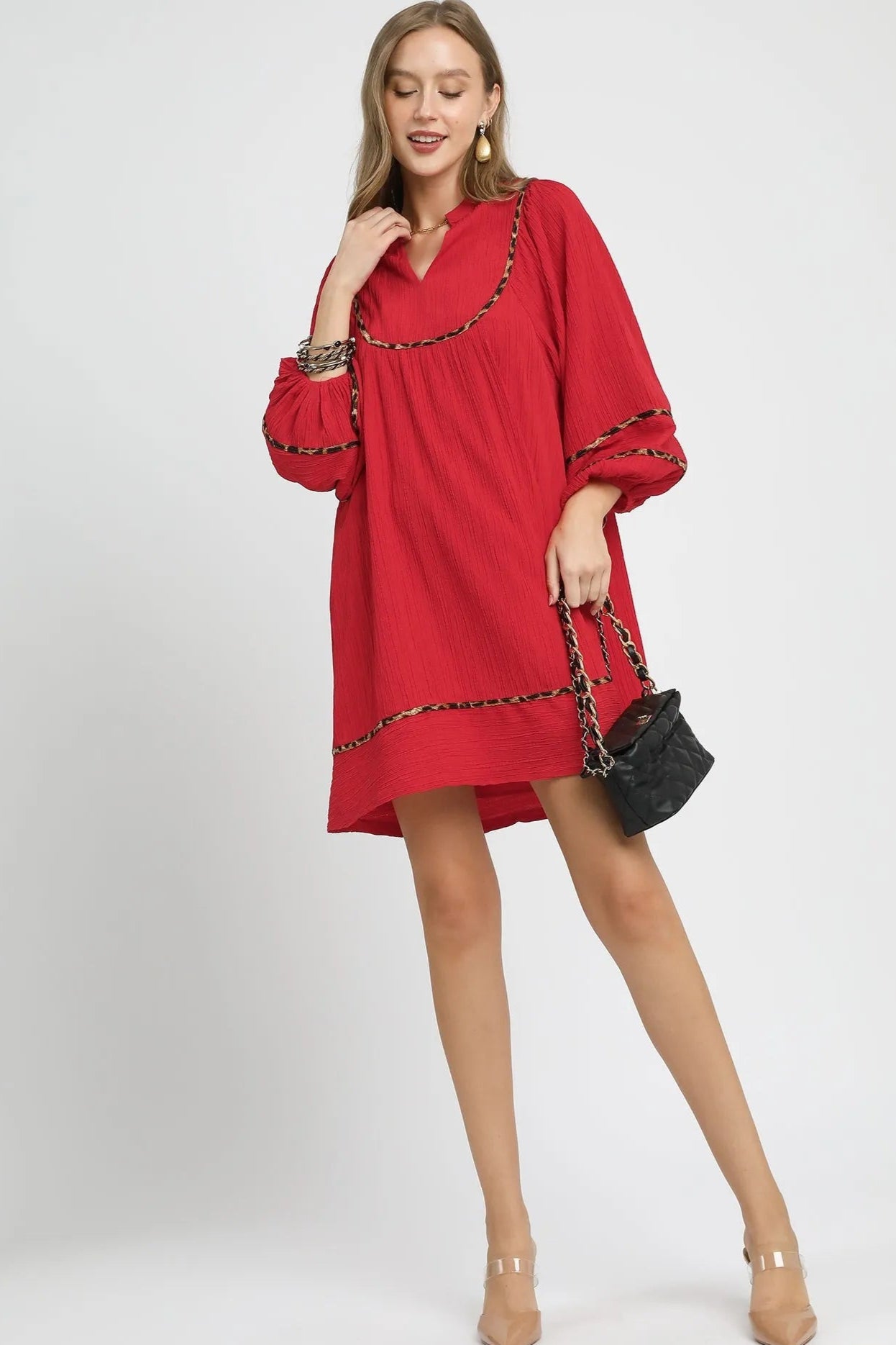 Woman wearing a red dress with a chain detail on a white background