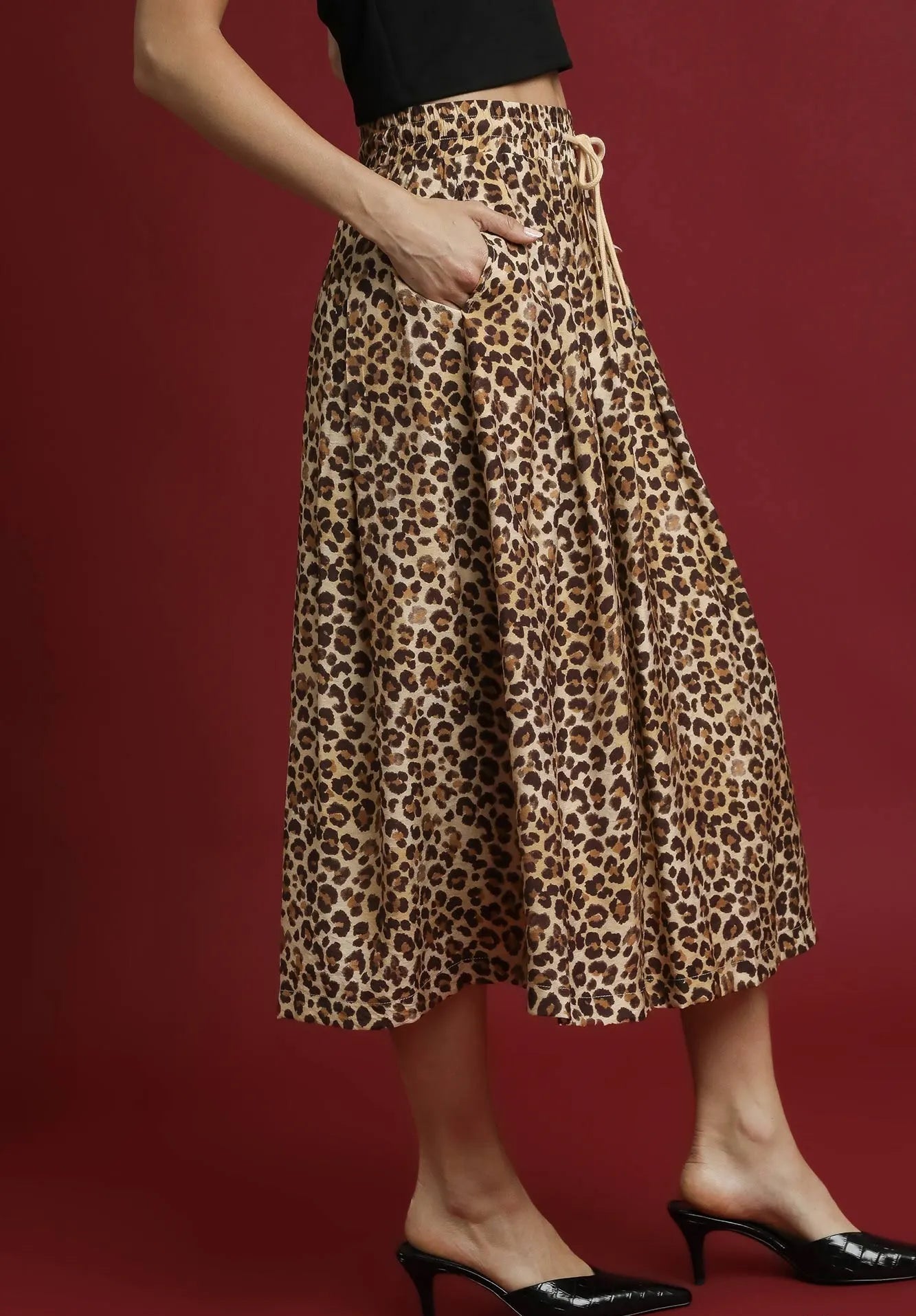 Person wearing a leopard print skirt on a red background