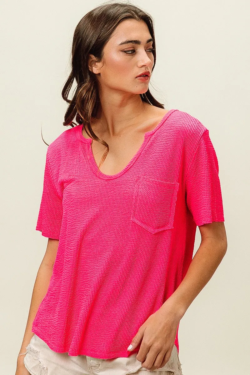 Woman wearing a bright pink textured top on a beige background