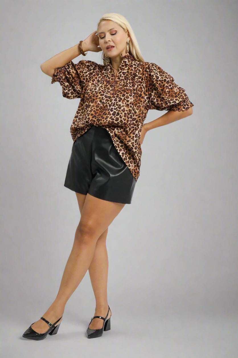 Woman wearing a leopard print blouse and black shorts on a white background