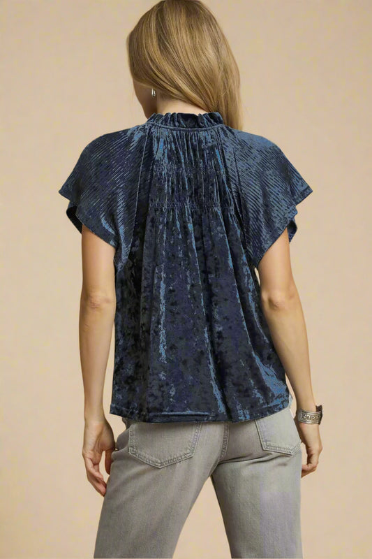 Woman wearing a blue top and gray pants on a beige background