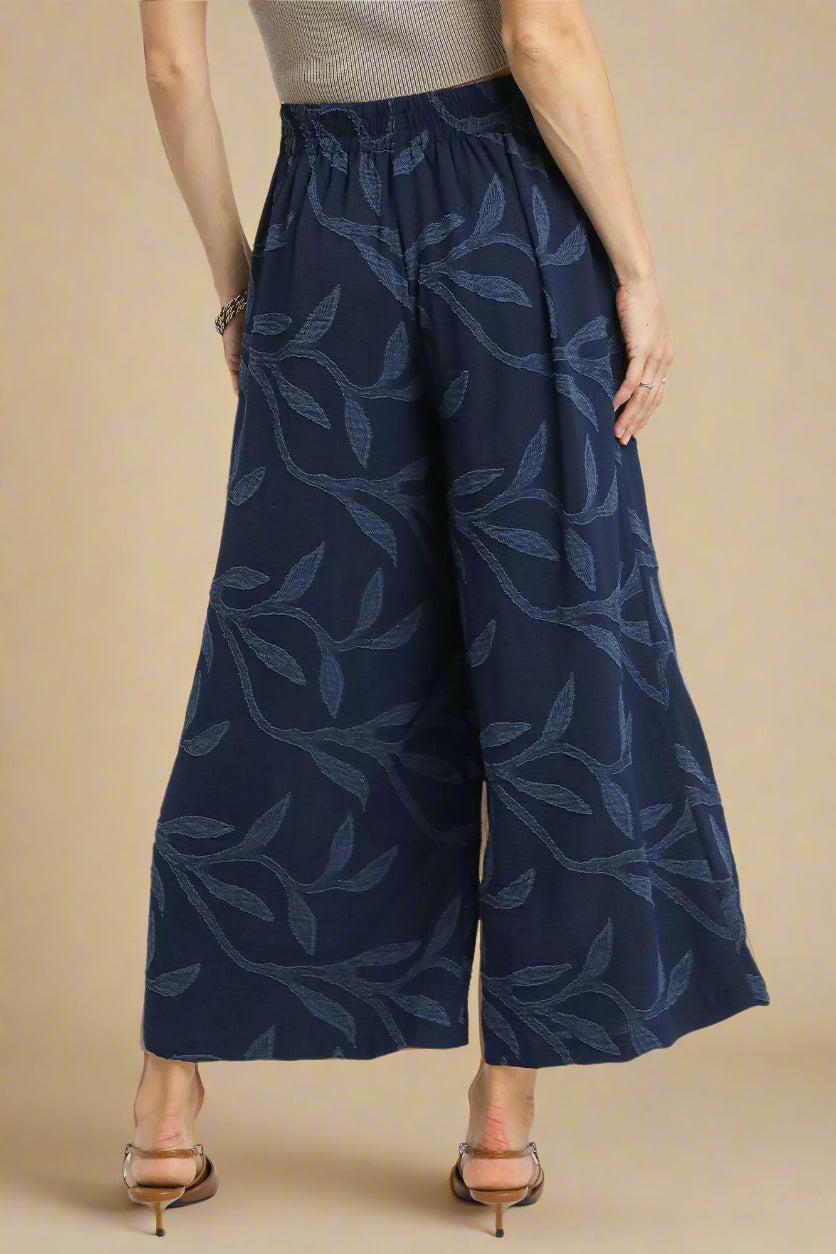 Navy patterned wide-leg pants worn by a person on a white background