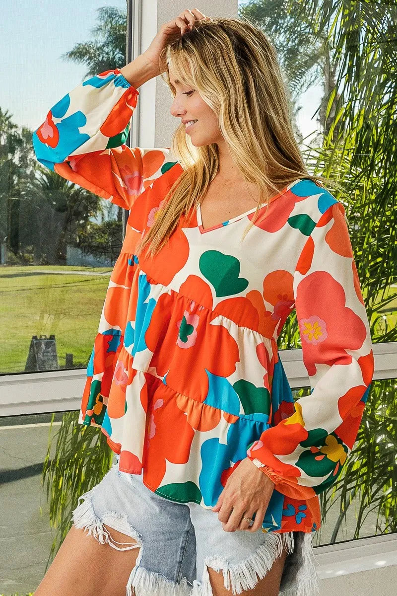 Woman wearing a colorful floral blouse with a blurred outdoor background