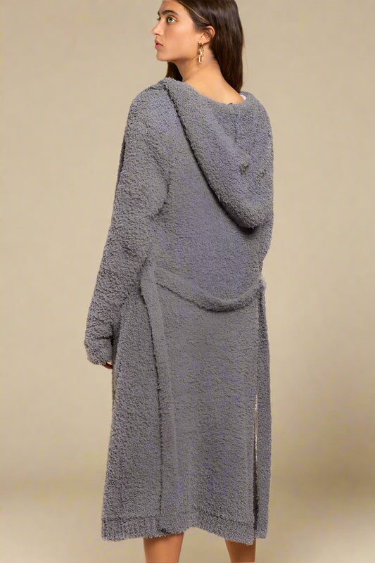 Woman wearing a gray textured cardigan against a beige background