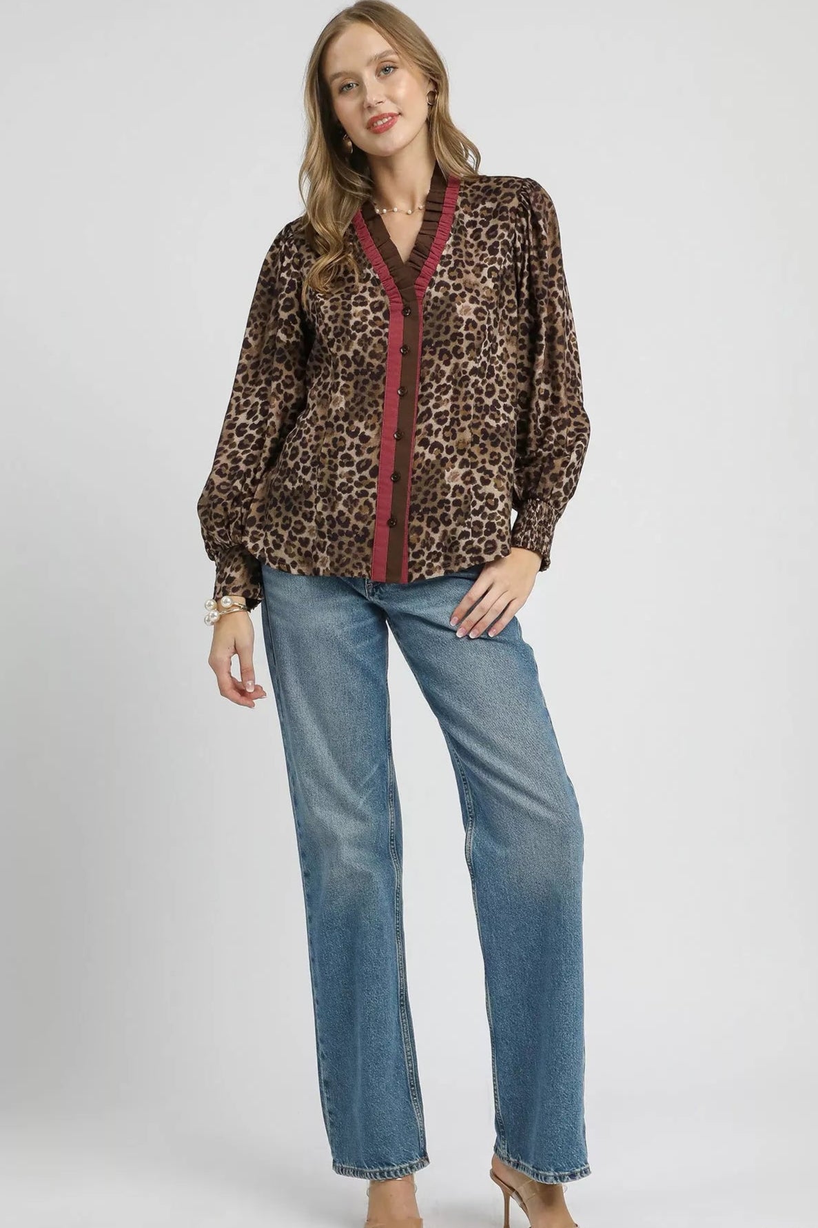 Woman wearing a leopard print blouse with red trim and blue jeans on a white background
