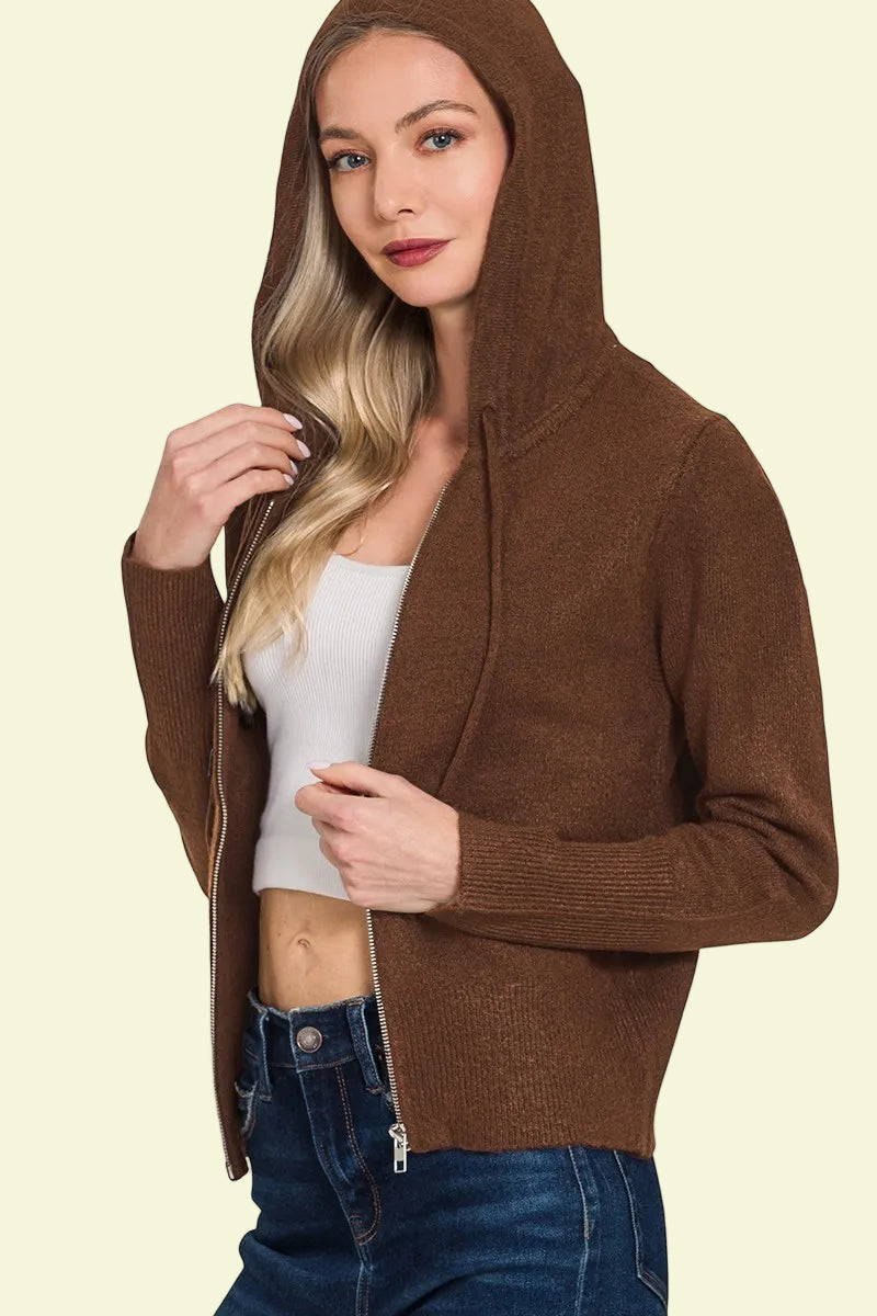 Woman wearing a brown hoodie over a white top and blue jeans on a white background