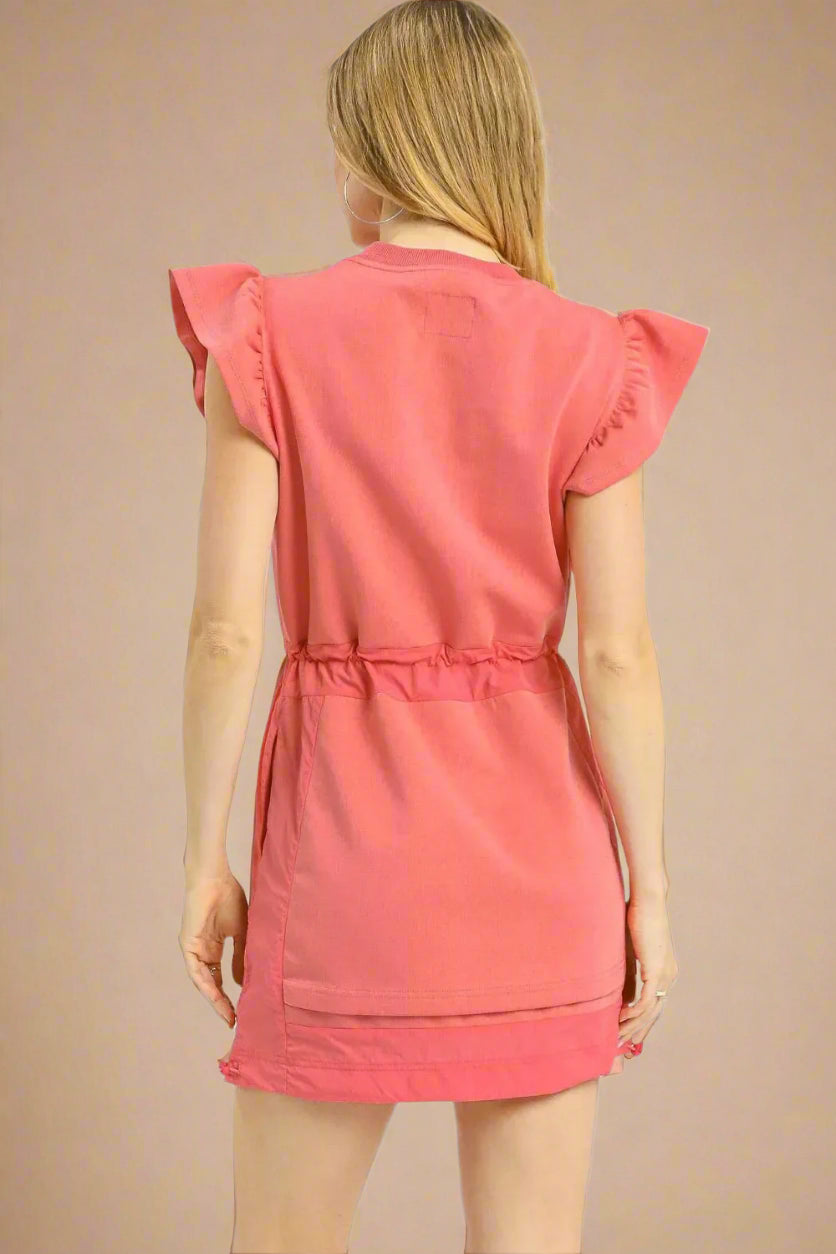 Woman wearing a pink dress with ruffled sleeves on a white background