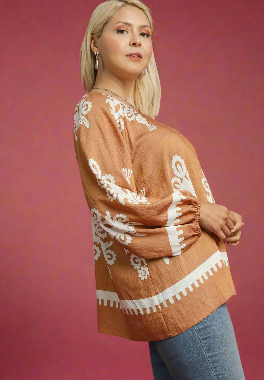 Woman wearing a brown plus-size top with white patterns on a red background