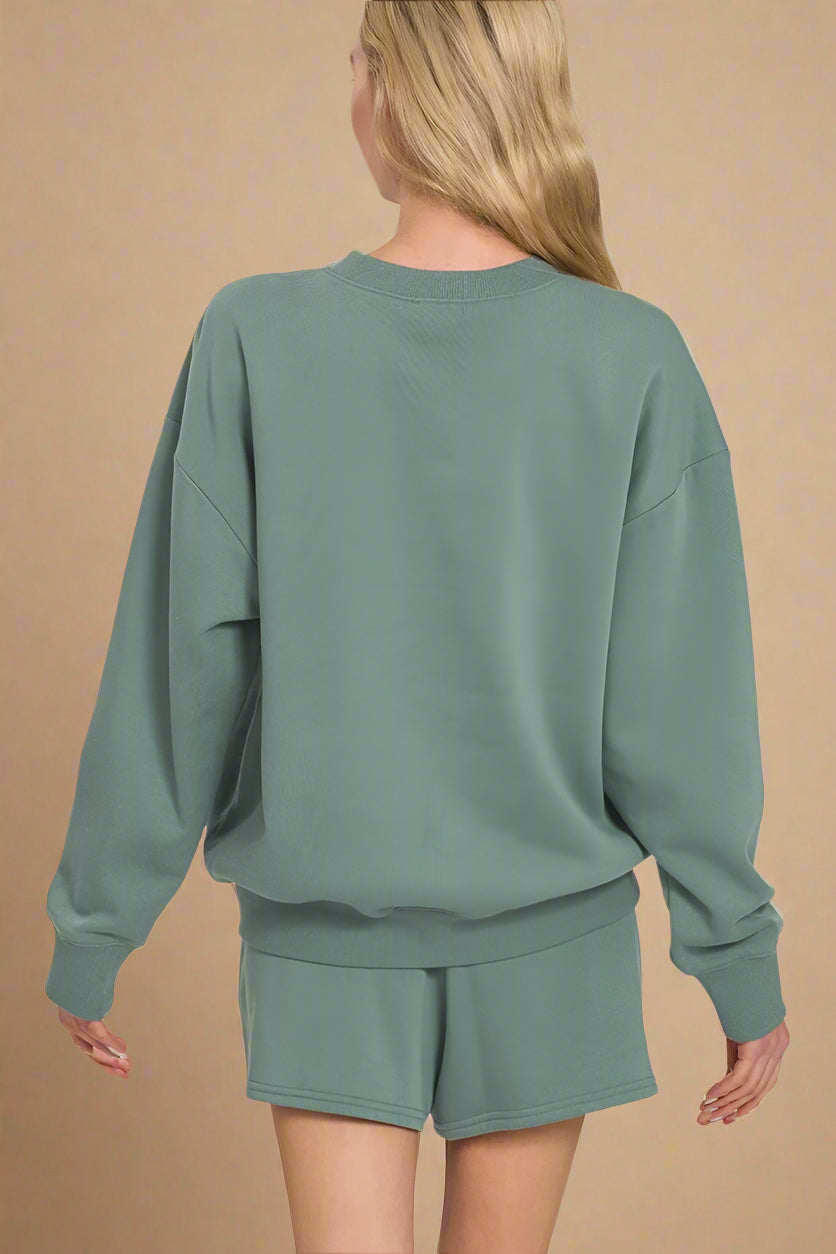 Person wearing an ash jade sweatshirt and shorts set on a white background