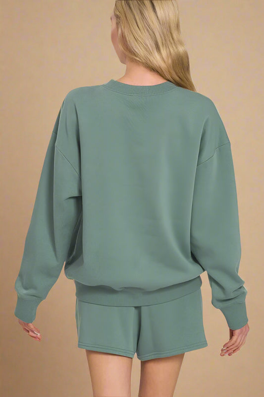 Person wearing an ash jade sweatshirt and shorts set on a white background