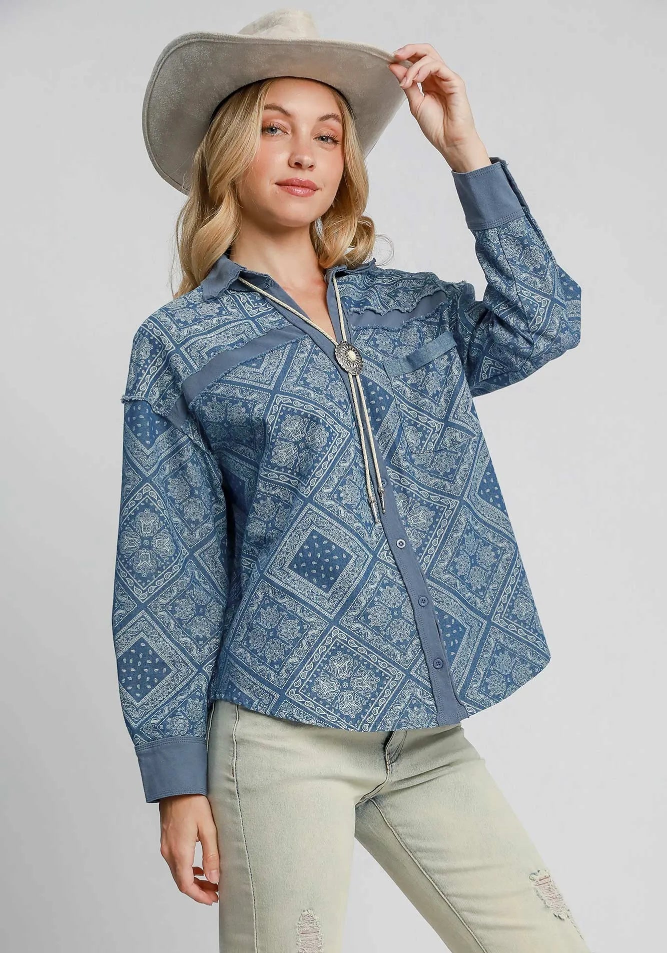 Woman wearing a blue patterned jacket and beige hat on a white background